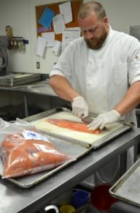 chef cutting up salmon for fried fish