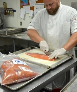 chef cutting up salmon for fried fish