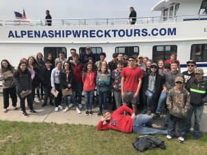 school group standing in front of a tour boat