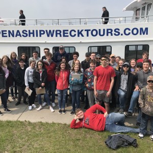 school group standing in front of a tour boat
