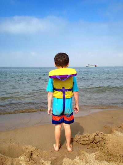 A child wearing a life preserver on beach