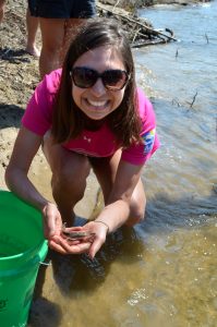 Woman in pink shirt holding a juvenile lake sturgeon