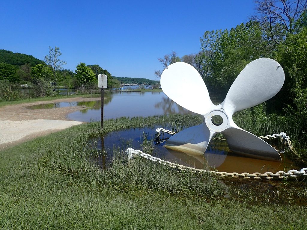 Large sculptural anchor sitting in a puddle caused by high water levels.
