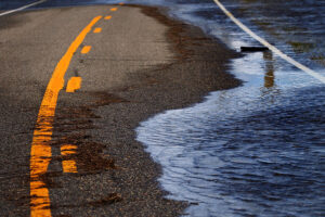 A flooded road, with yellow center line being encroached by water.