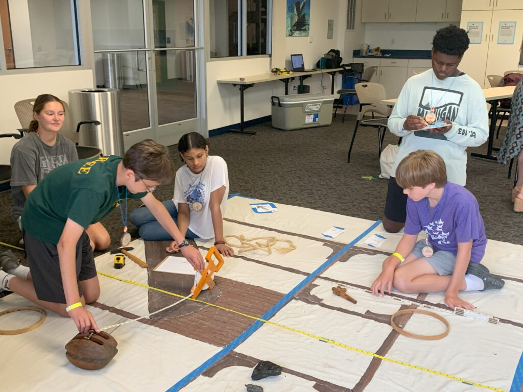 Campers measure artifacts as they work in teams to create a map of a shipwreck.
