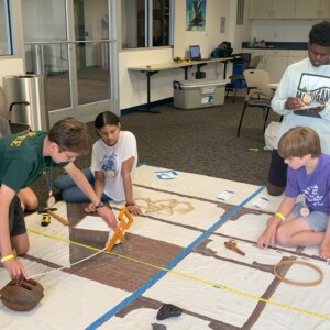 Campers measure artifacts as they work in teams to create a map of a shipwreck.