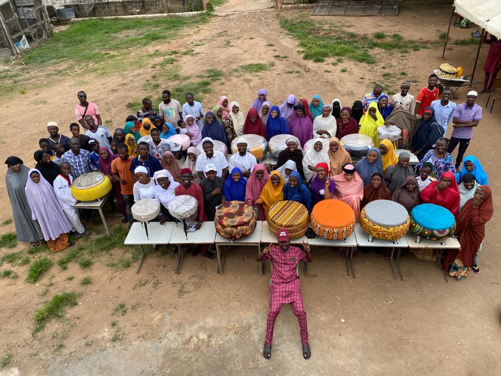 A group of Nigerian people smile as they pose with furniture made of recycled rubber tires.