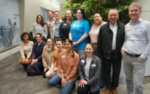 A group of 14 workshop participants pose together in a conference center foyer