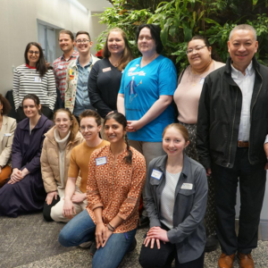 A group of 14 workshop participants pose together in a conference center foyer