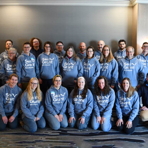 A group photo of staff wearing a Sea Grant hoodie