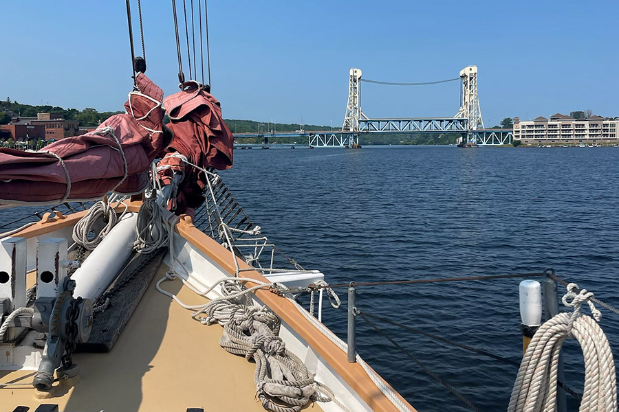 A sailboat looking out at the bow, with a bridge in the background.