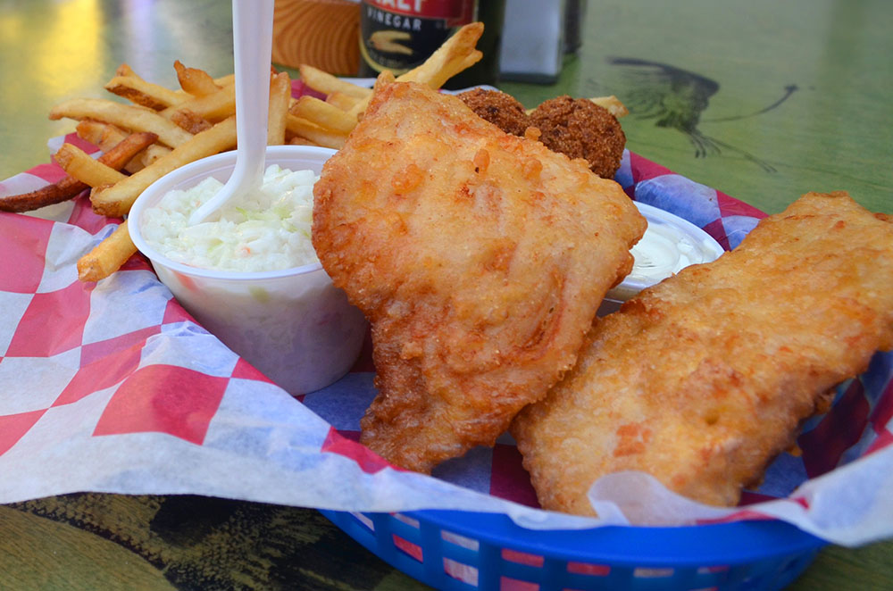 Fried fish on a plate with french fries and coleslaw.
