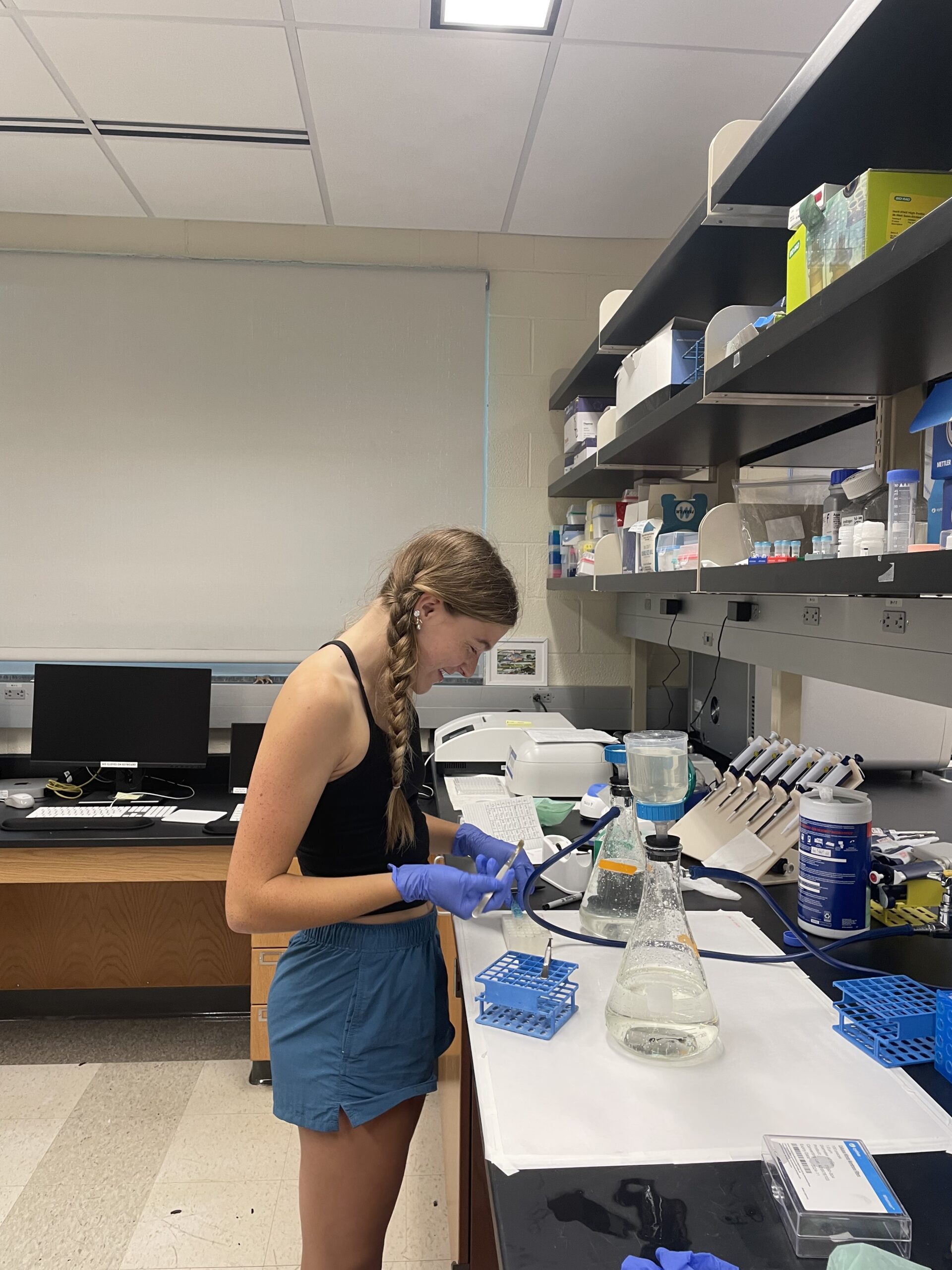 Annie stands in front of a lab bench, processing a water sample