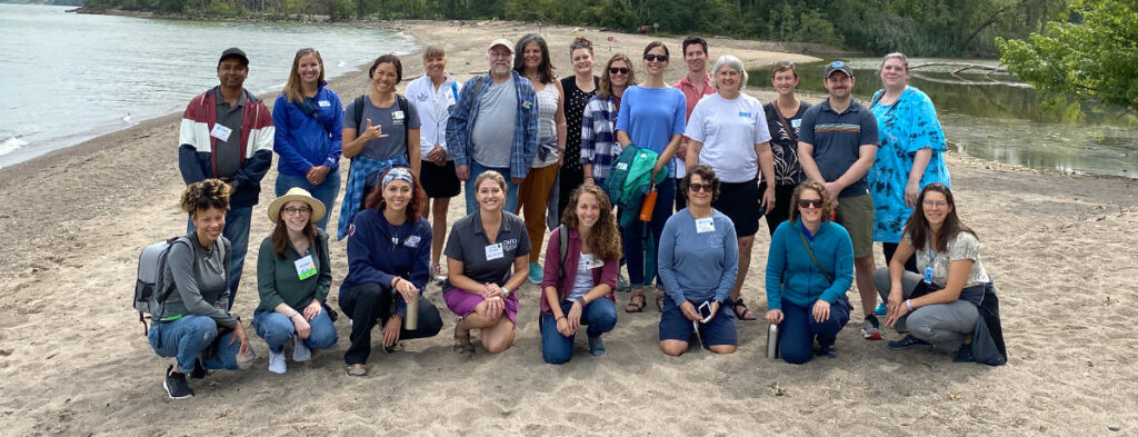 A group of partners pose for a team photo along the shores of Lake Erie