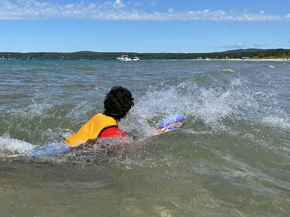 a person swimming in a lake and catching a wave on a sunny day