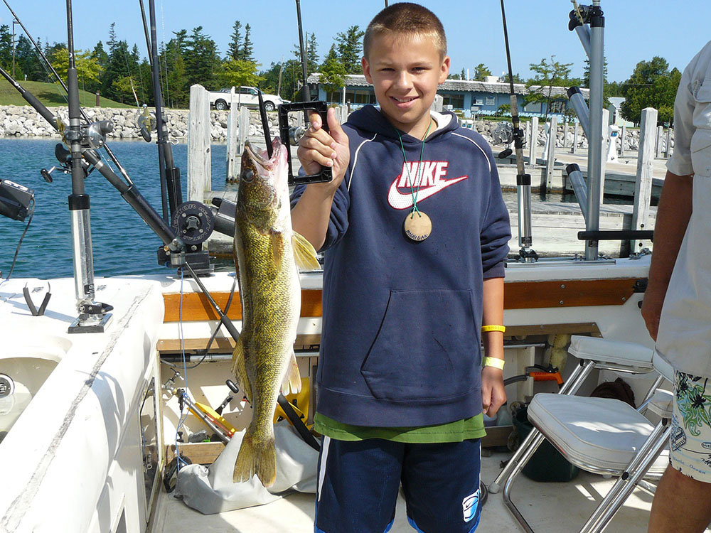 A fisher holds a walley caught on a fishing trip on a boat