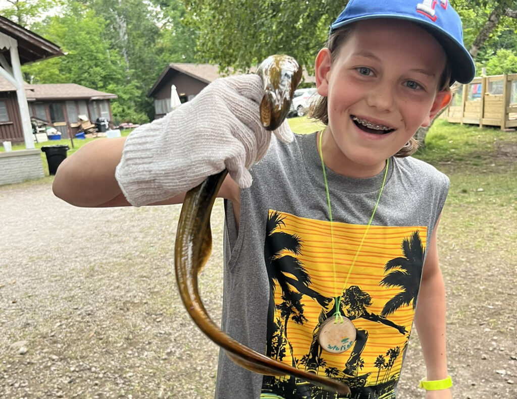 Teen wearing a white glove holds a live sea lamprey.