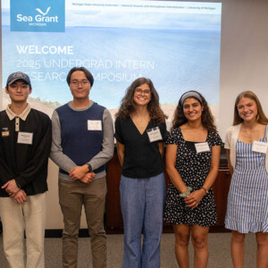 Students standing in front of a screen for a group photo at the symposium