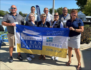A group of marina reps hold a large flag with a boat on it.