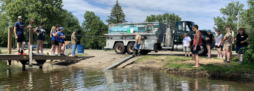 A group of students observing a fish stock release from a DNR truck
