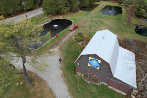 An aquaculture farm as seen from overhead, 4 ponds surrounding a barn with a white roof