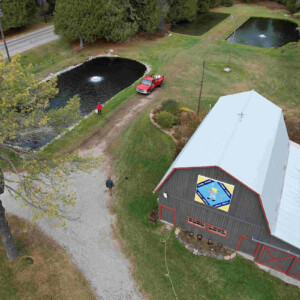 An aquaculture farm as seen from overhead, 4 ponds surrounding a barn with a white roof