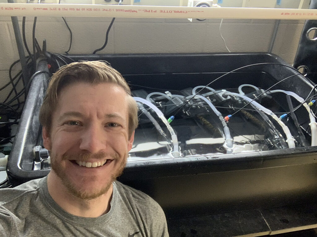 Researcher Scott Jackson stands in front of research equipment with walleye inside