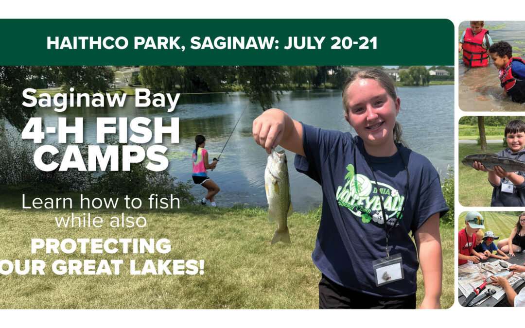 A student holds up a fish that they caught at camp