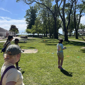 participants learning how to fish near a playground with a lake in the background