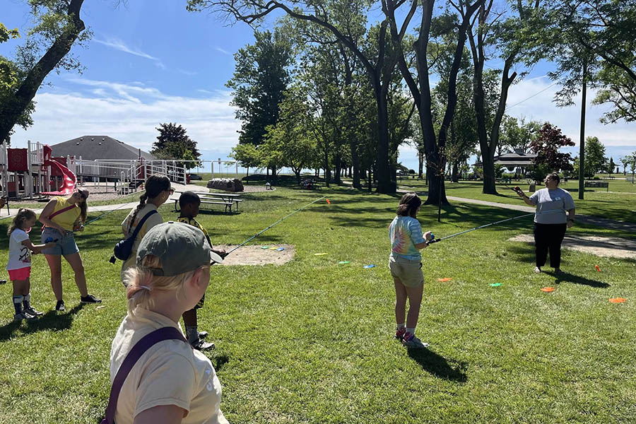 participants learning how to fish near a playground with a lake in the background